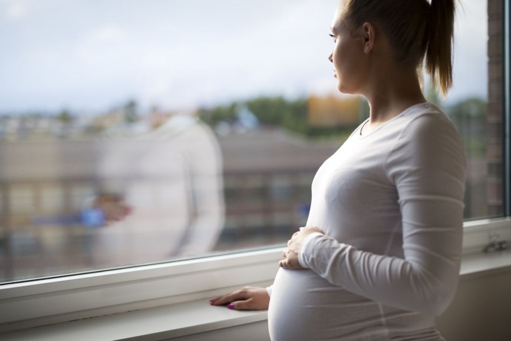 mujer embarazada mira por la ventana