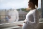 mujer embarazada mira por la ventana