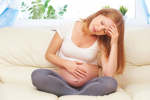 Mujer sentada tomando su barriga y frente-3. Dolor lumbar y de pelvis en el embarazo