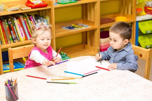 niños sentados en una mesa, con cuadernos y colores.