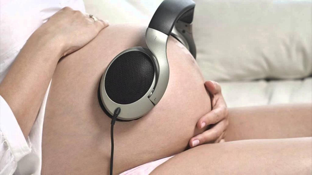 mujer embarazada coloca auriculares para que su bebé escuche música. ¿Puedo ir a un concierto si estoy embarazada?