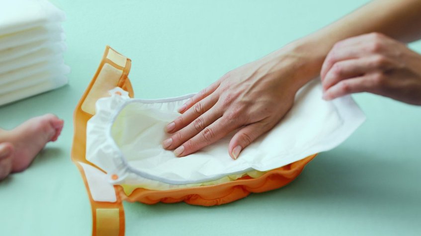 pañal y mano de una mujer- Mi bebé no defeca diariamente, ¿Es normal?