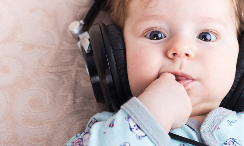 Bebé acostado con auidifonos- Cómo calmar a un bebé
