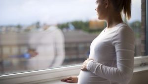 Una mujer embarazada que mira desde la ventana